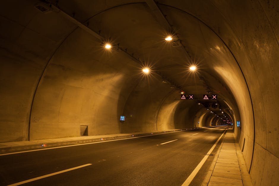 A long exposure photograph of a dimly lit urban tunnel with light streaks and reflections.